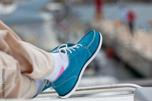A pair of human legs in pants and bright blue topsiders