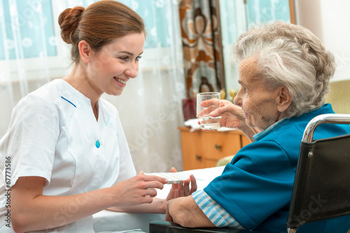 female nurse giving senior woman medical pills