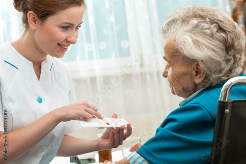 female nurse giving senior woman medical pills