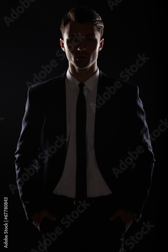 Handsome business man in black suite, backlight