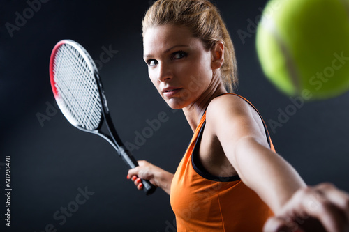 Portrait of beautiful woman playing tennis indoor.