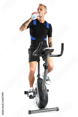 Trening na rowerze treningowym, mężczyzna pije wodę