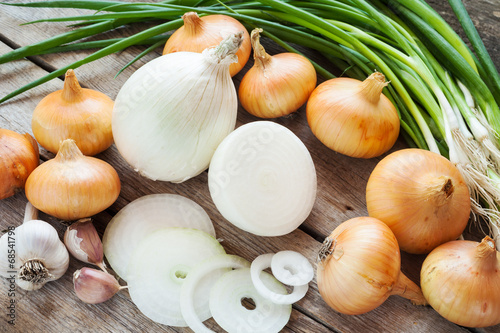 different onions and garlic on wooden table