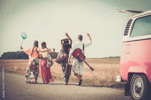 Multi-ethnic hippie friends with guitar and luggage