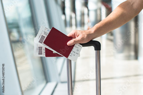 Close up of male hands holding passports and boarding pass at