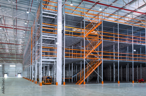 Mezzanine inside big automated warehouse, interior with modern tall shelving and racking