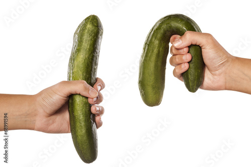 women hands holding distorted and normal cucumber on white