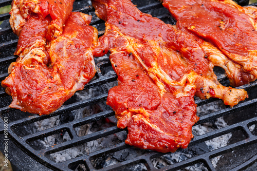 Grilling pork steaks on barbecue grill
