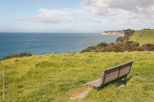empty bench on green meadow above Long Bay