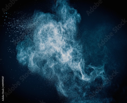 Blue powder exploding isolated on black