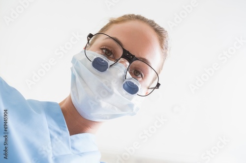 Dentist in surgical mask and dental loupes