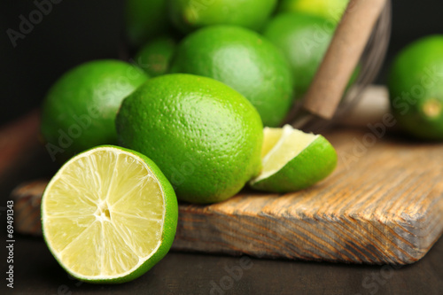 Fresh juicy limes on wooden table, on dark background