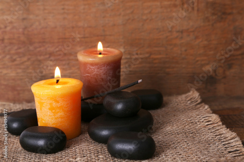 Spa stones with candles on wooden background