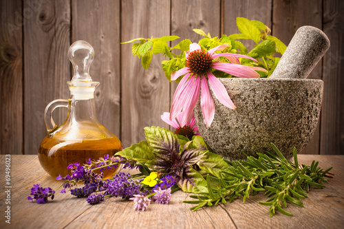 Healing herbs with mortar and bottle of essential oil