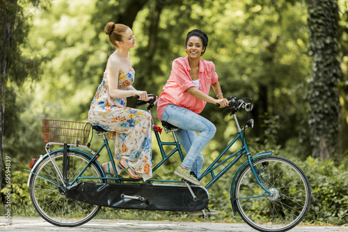 Young women riding on the tandem bicycle