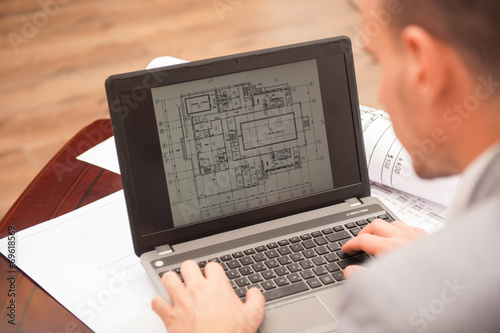 Close-up portrait of laptop with blueprints