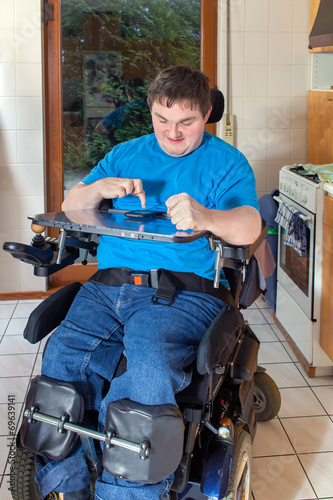 Spastic young man confined to a wheelchair, dialing a phone numb