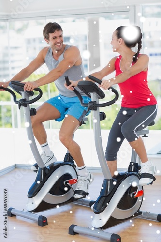 Smiling young couple working out at spinning