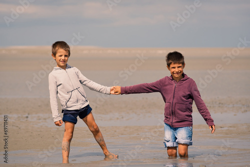 Young brothers having fun with quicksand on the beach in front o