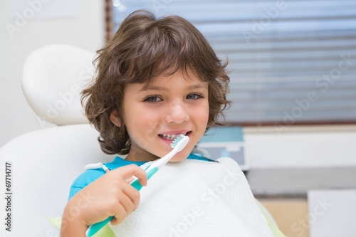 Little boy in dentists chair using toothrbrush