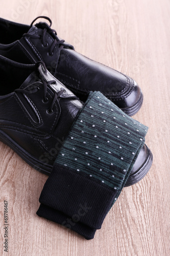 Black man's shoes and pair of socks on wooden background