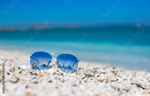Close up of colorful blue sunglasses on tropical beach.