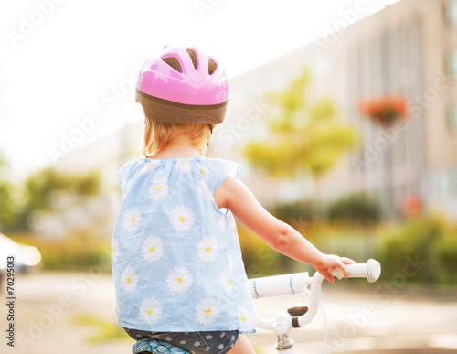 Baby girl riding bicycle. rear view