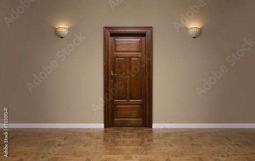 Closed wooden door in the empty room with copy space
