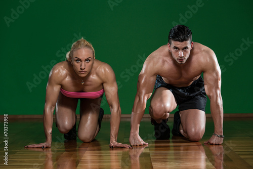 Strong Muscular Couple Kneeling On The Floor