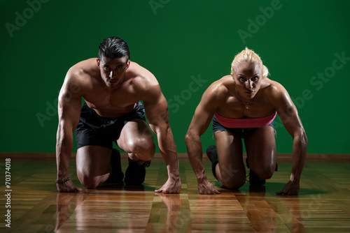 Strong Muscular Couple Kneeling On The Floor