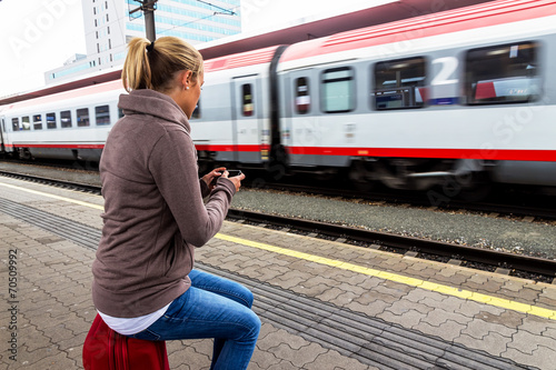 Frau wartet auf Zug und schreibt SMS