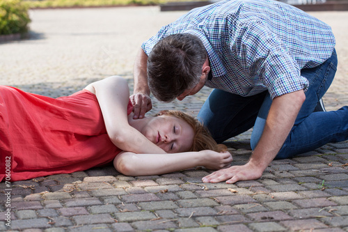 Man checking pulse of fainted girl