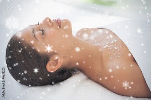 Brunette lying on massage table with salt scrub on chest