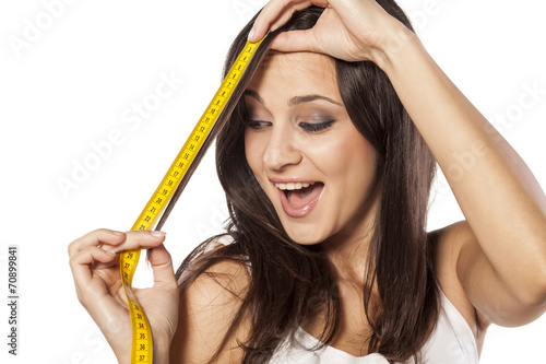 Happy attractive girl measured her hair with a tape measure