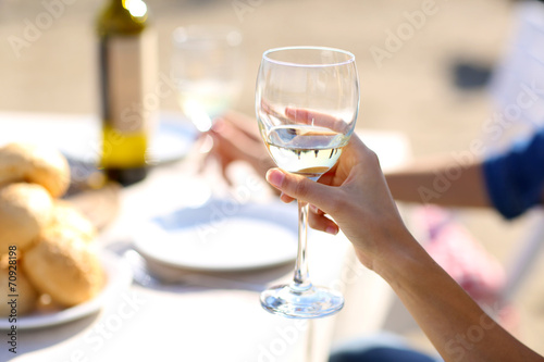 Friends enjoying drink at outdoor restaurant. Hand with glass,