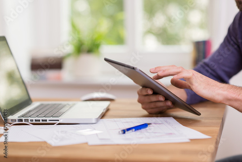 mann arbeitet mit tablet und notebook zu hause