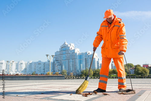 Man road sweeper caretaker cleaning city street with broom tool