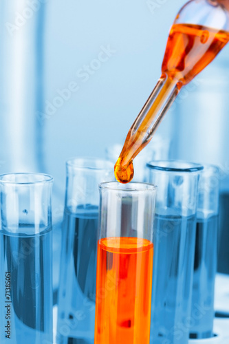 Laboratory pipette with drop of color liquid over glass test