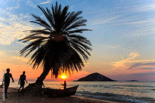 Sunset with palm tree and boat at the beach in africa