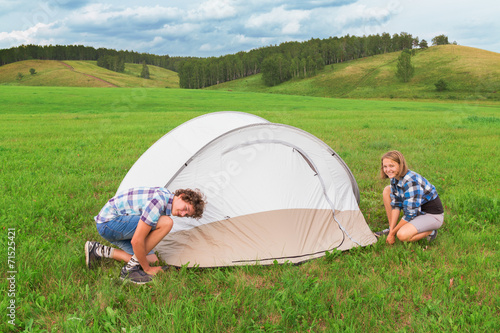 Teenage boy and girl arranges tourist tent