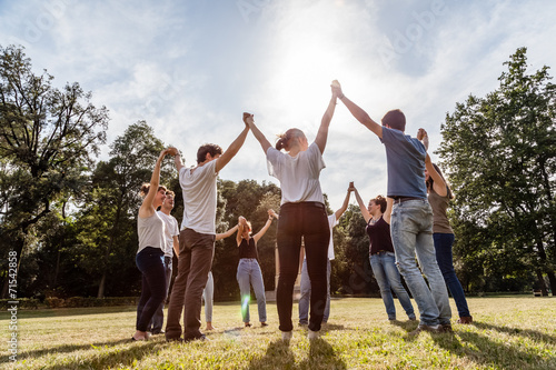 Group of friends at the park holding hands and rise up