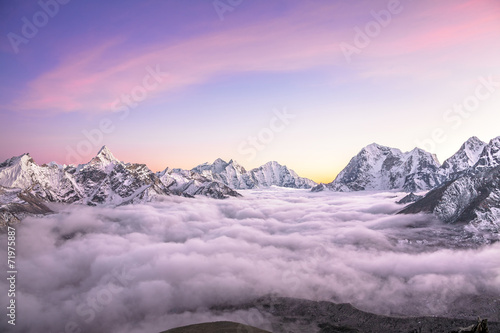 Mountain valley filled with curly clouds at sunrise. Himalayas.