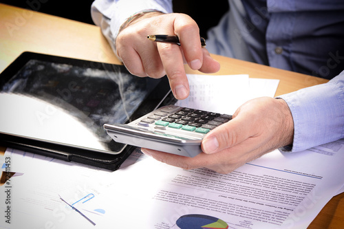 Businessman Using Calculator In Office