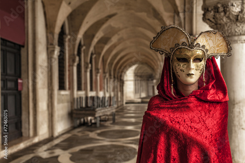 Woman with a red robe wearing a mysterious mask at Famous Venetian Festival