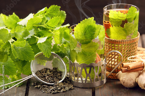 Hot green tea in a glass on a wooden background with lemon balm