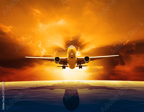 passenger jet plane flying over beautiful sea level with sun set