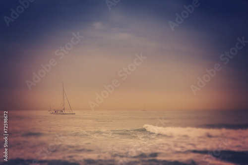 blurred retro image of small yacht in the sea, with tilt shift e