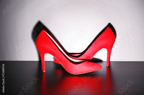 Pair of woman's red shoes on floor on light wall background