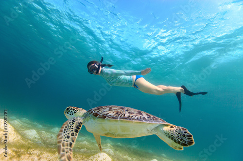 Young girl snorkeling with sea turtle