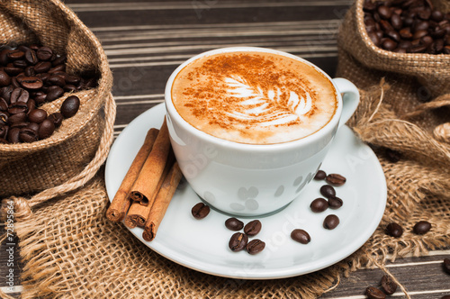 Cappuccino in a white cup with cinnamon and drawing on milk